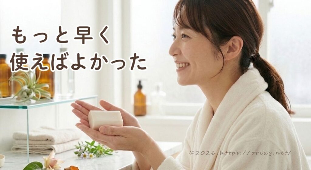 バスローブを着た女性がバスルームでジャムウ石鹸を手に持っているイメージ。