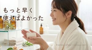 バスローブを着た女性がバスルームでジャムウ石鹸を手に持っているイメージ。