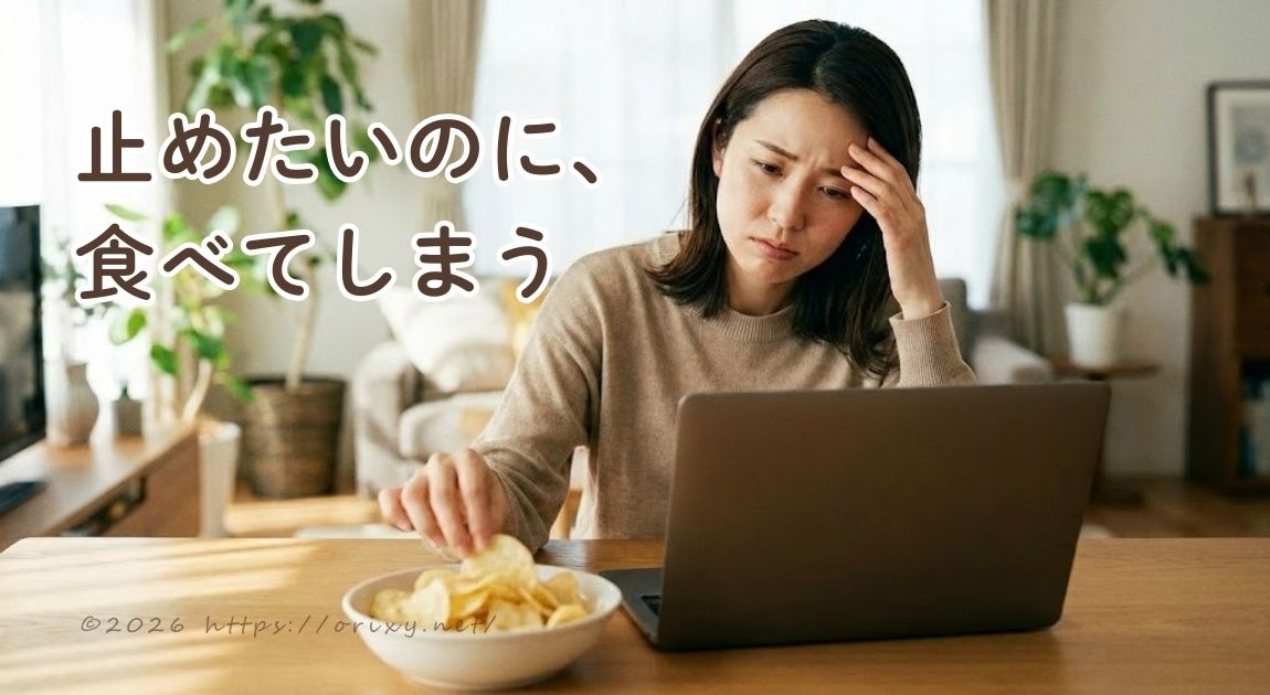 更年期の過食に悩む女性が、パソコン作業をしながらついお菓子を食べてしまう様子。自分の意思を責めるのではなく、心をゆるめて整えるためのヒント。
